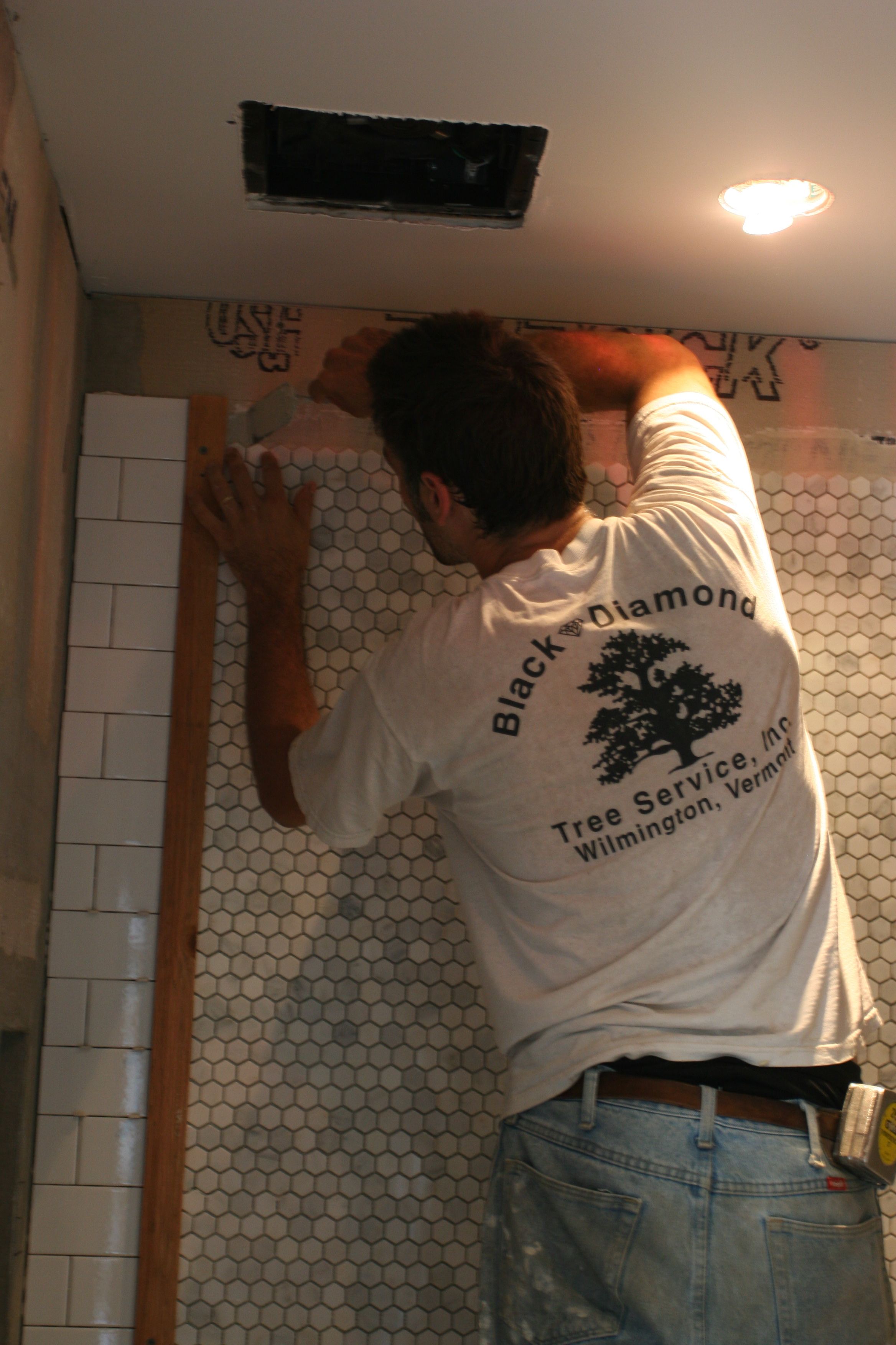 Carefully scraping back the excess thin-set so tomorrow's tile can be applied to a fresh, smooth wall.