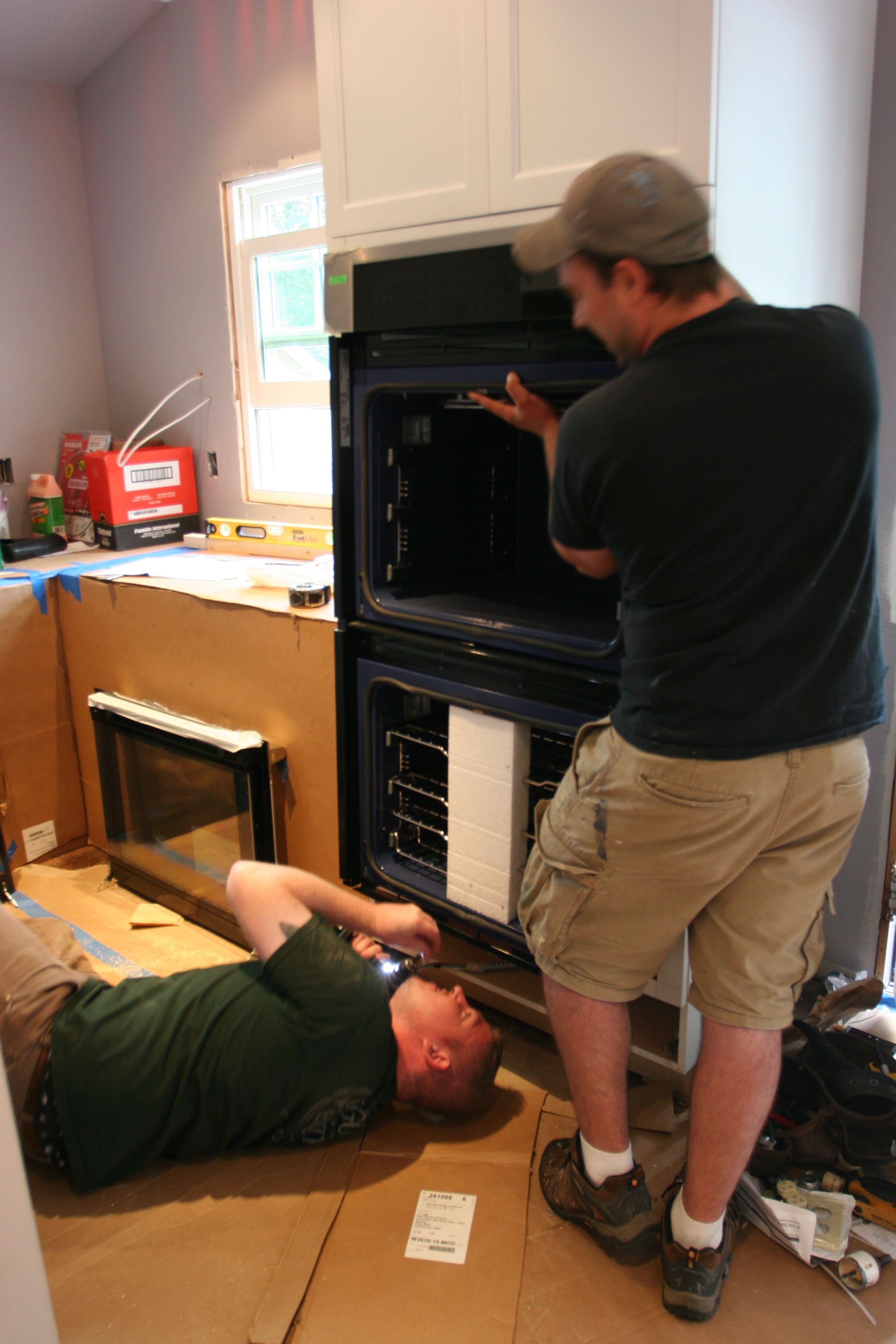 Brad in his favorite spot - the floor - installing the safety bracket for the wall ovens while Dave held the 200+ lb. appliance by himself.