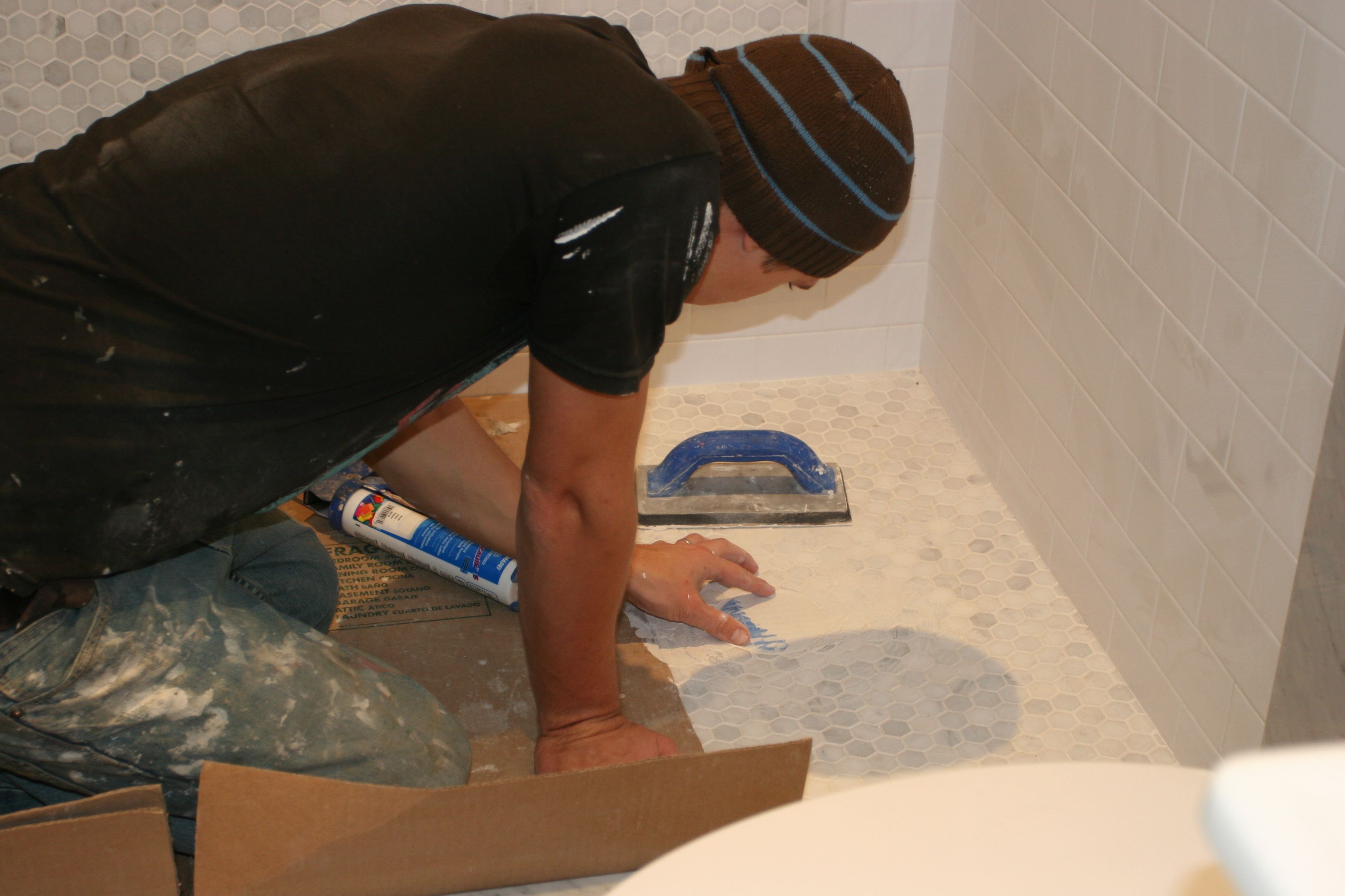 J.J. finishing up the shower drain (hidden underneath the grout).