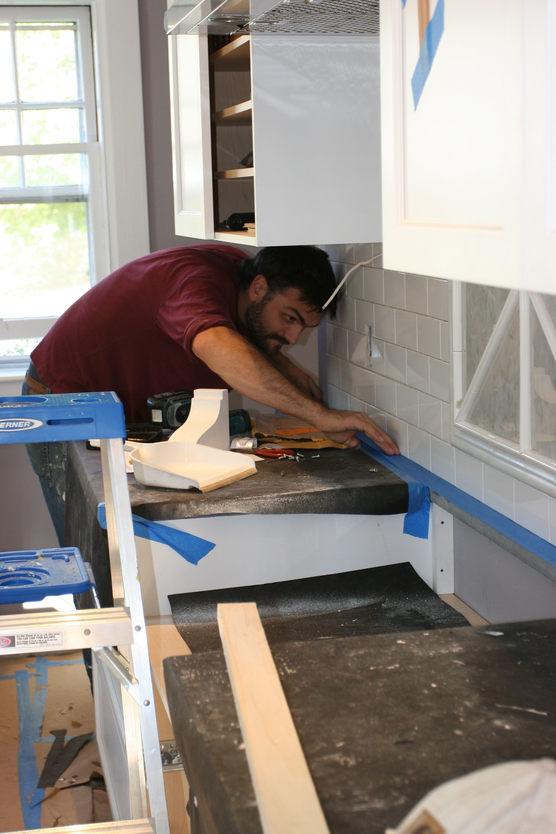 Caleb laying down some blue tape to protect our countertops from errant grout (or sealer, later).