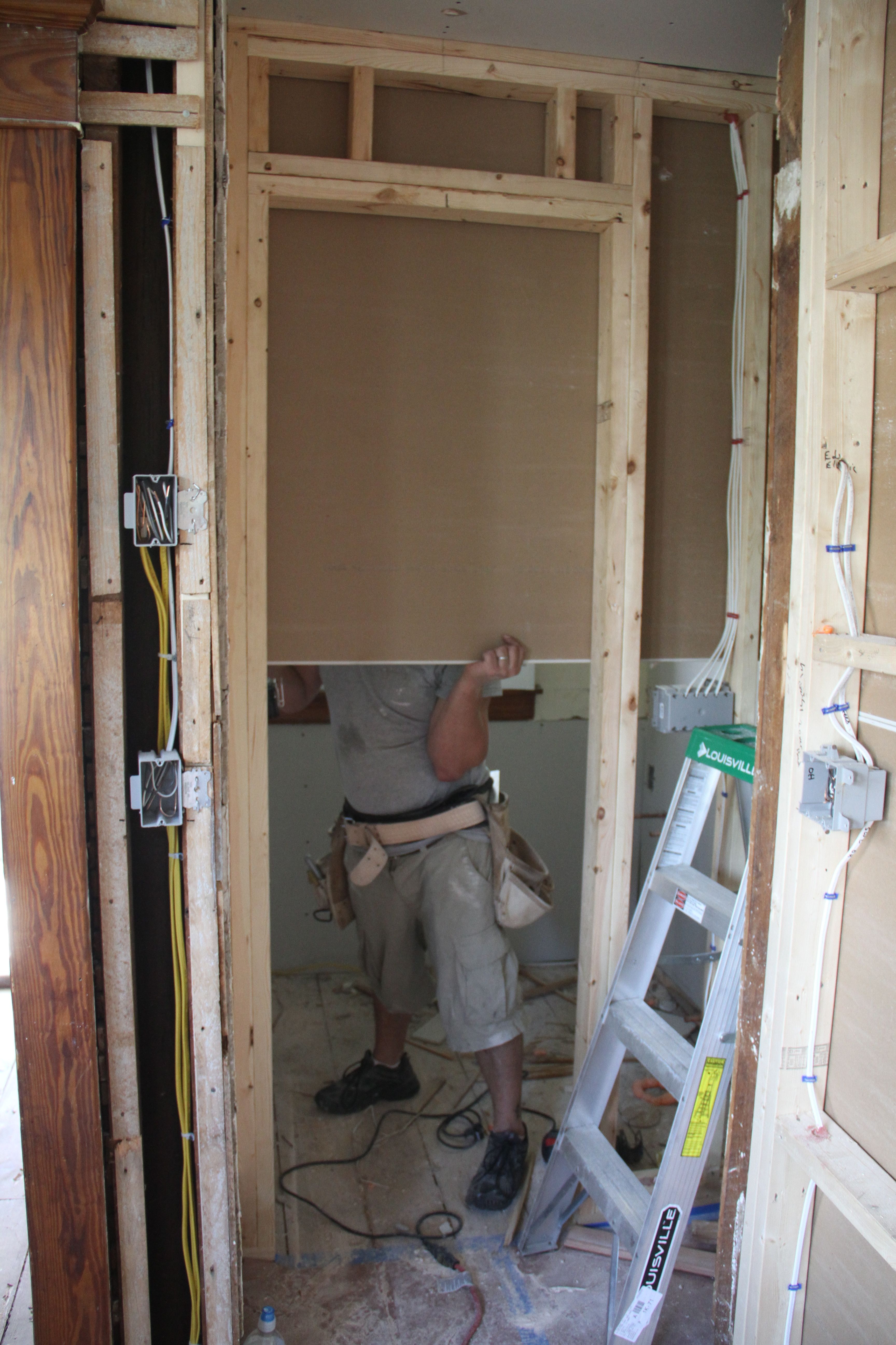 Brian affixing the 'rock to the inside of the bathroom.
