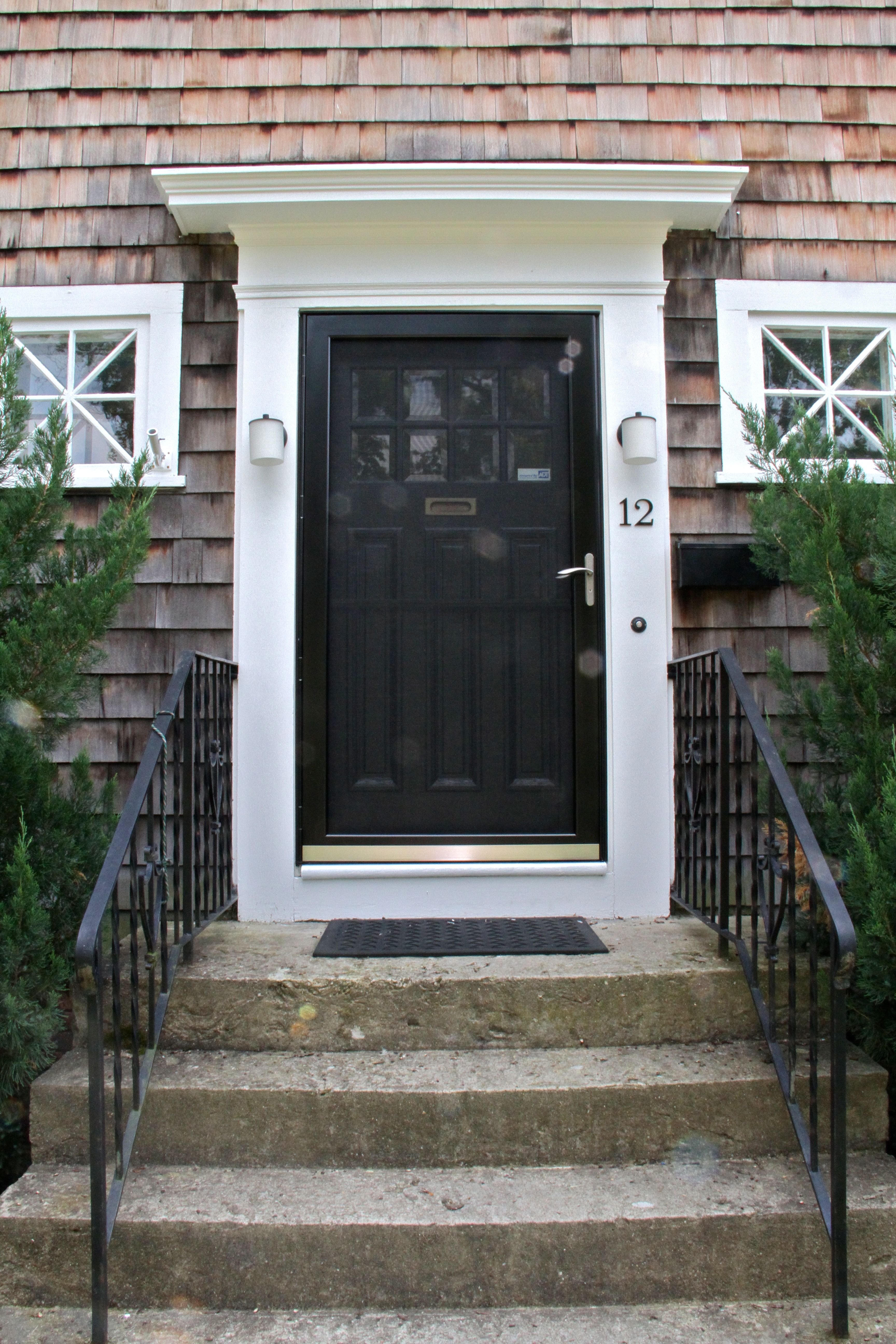 AFTER: The front door, with its storm door in place. The old one was broken, dingy, and white. This one lets you know that the extra-wide, original front door is black, glossy, and full of details.