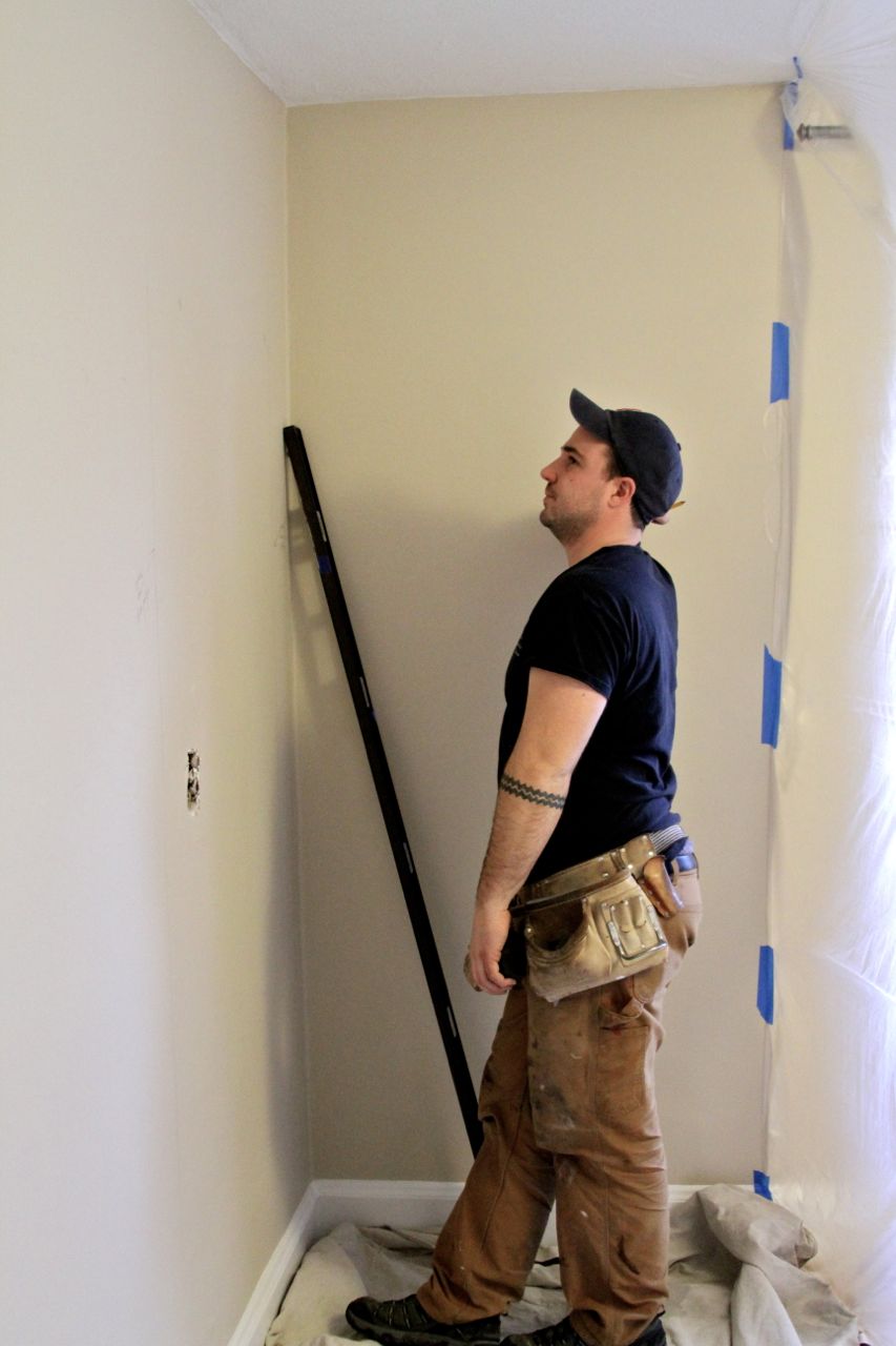 DURING: Dave, assessing the best place to make a hole for the soon-to-be-closet door.  This wall used to have a light switch for exterior lights. Yes, in the bedroom.
